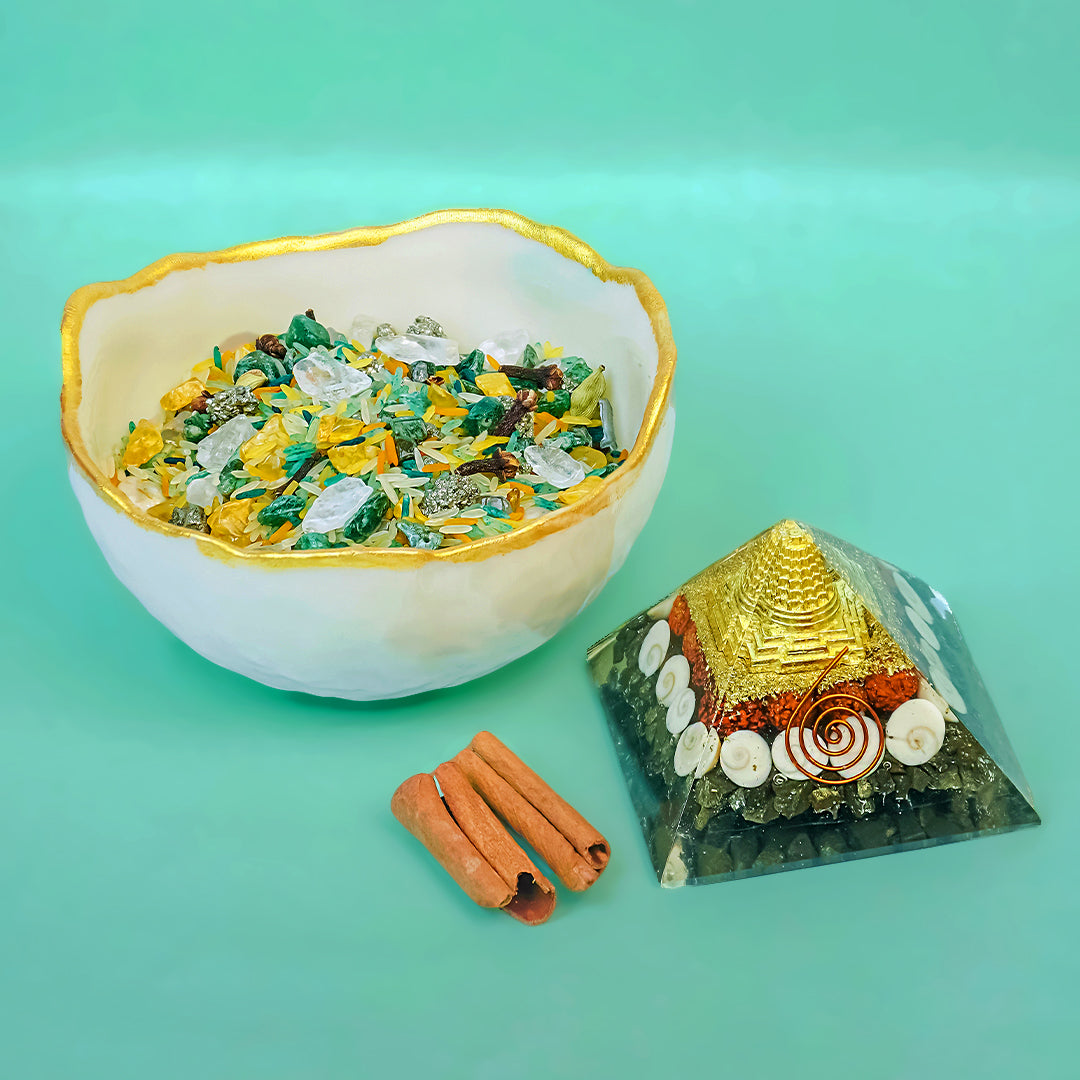 Selenite bowl with colorful stones, cinnamon sticks, and a pyramid-shaped crystal