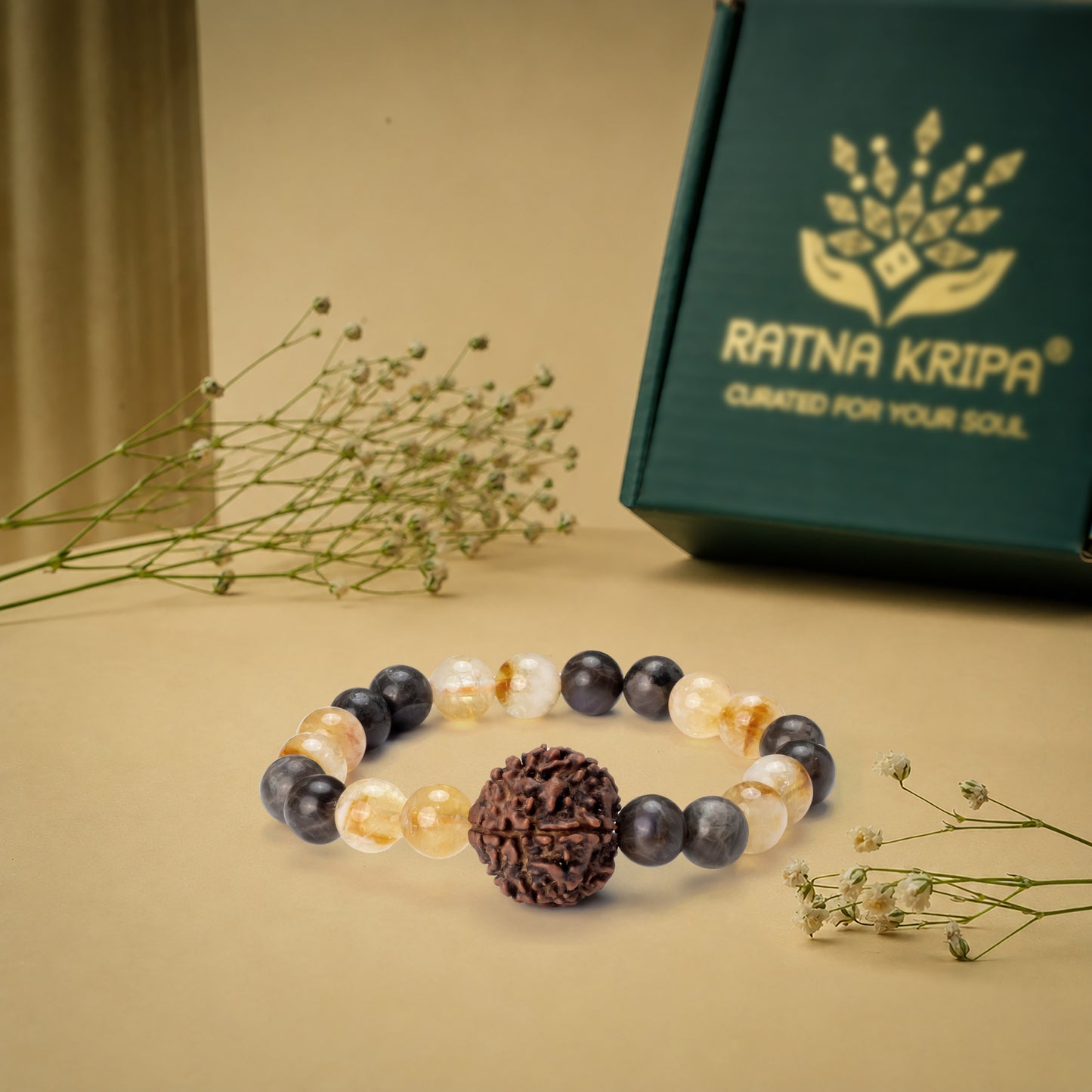 Beaded bracelet with a large central bead on a beige surface with a 'Ratna Kripa' box in the background.