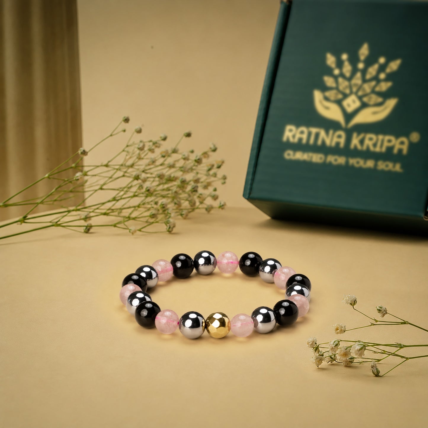 Multicolored beaded bracelet on a beige surface with a 'Ratna Kripa' branded box in the background.
